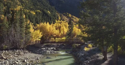 Fall Colorado Mountain river fly up bridge river Stock Footage 68177494