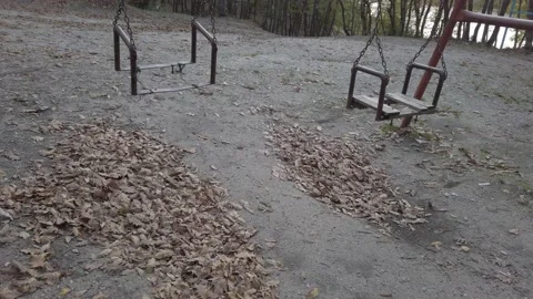 Fall dark forest, playground in clearing. Old rusty metal swing swaying in wind Vídeos de archivo 142393190
