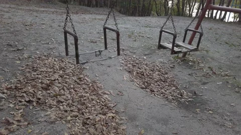 Fall dark forest, playground in clearing. Old rusty metal swing swaying in wind Stock Footage 142393625