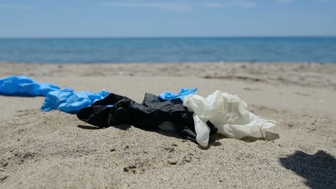 Fall down mask and plastic gloves on seacoast,coronavirus pollution slow motion Stock Footage 129867266