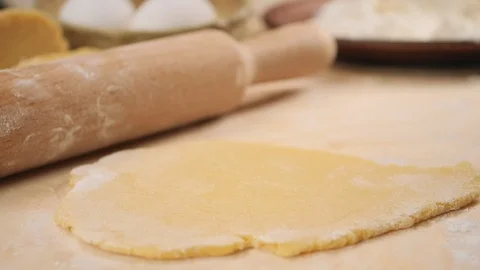 A fall of flour on the dough against the background of rolling pin, eggs, a p Stock Footage 124870241