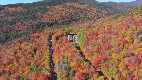 Fall forested hills with winding Kancamagus Highway and parking area, US Видео 348248564