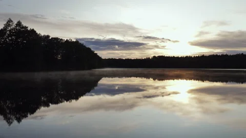 A fall landscape of a lake in the middle of a forest during the setting sun. 库存影片 220566572