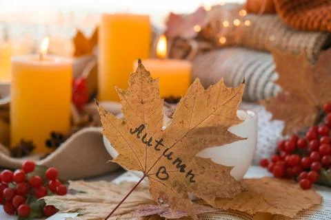 Fall maple leaf with text AUTUMN on Autumn season design concept. Candles on Stock Photos