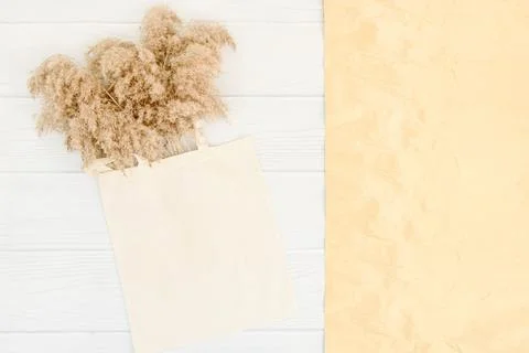 Fall mockup with tote bag blank and dry reeds on white wood table with golden Stock Photos
