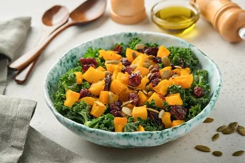 Fall salad with kale, roasted pumpkin, seeds and dried cranberries in bowl. G Stock Photos