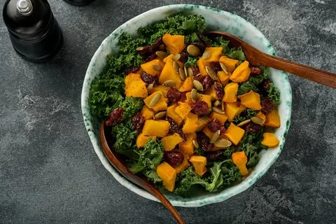 Fall salad with kale, roasted pumpkin, seeds and dried cranberries in bowl. G Stock Photos