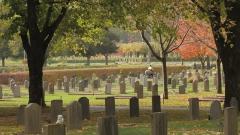Fall Scene at Graveyard, Cemetery caretaker Lawn Mowing in Background, Wide Shot 스톡 동영상 240998569