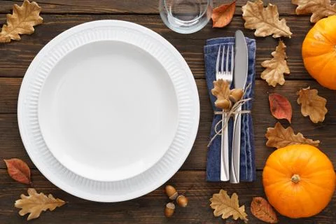 Fall season table setting with pumpkins, leaves and cutlery. Stock Photos