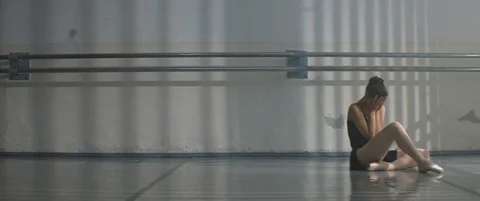 Fallen ballet dancer stretches her foot and cries in dance hall, feel pain Stock Footage 120579376