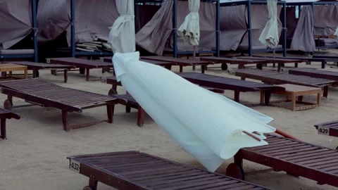 Fallen beach umbrella lying on sand among wooden sun loungers in Jurmala resort Stock Footage 344355529
