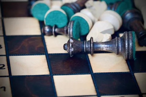 Fallen Black Queen and Chess Pieces on Wooden Board Symbolizing Defeat and .. Stock Photos