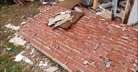 Fallen brick wall pan tilt reveals gutted house destroyed by storm surge Stock Footage 98834625