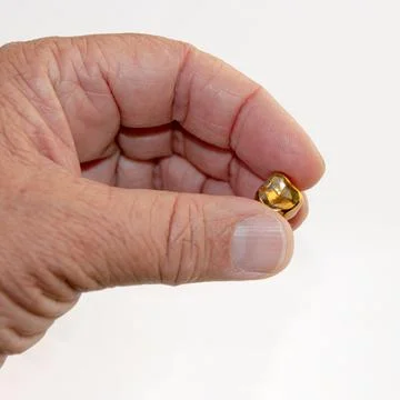 A fallen gold tooth in the hand of an elderly man.. Stock Photos