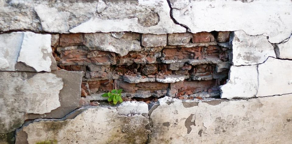 Fallen off plaster from a brick wall. The background of the old plastered wal Stockfoto's