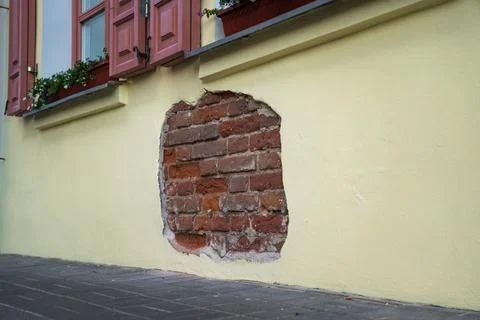 The fallen plaster from the wall of the building, brickwork is visible Stock Photos