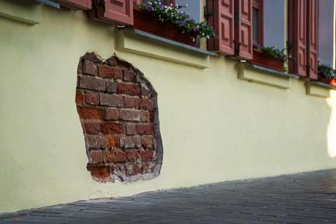 The fallen plaster from the wall of the building, brickwork is visible Stock Photos
