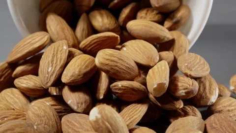 Falling almonds on grey background. Almond nuts fall on table. Brown almond nuts Stock Footage 299272231