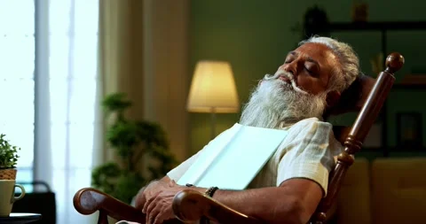Falling asleep while reading, Indian mid age bearded man on relaxing chair Stock Footage 342779360