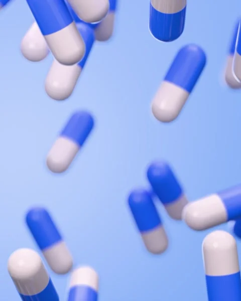 Falling blue and white capsule pills on blue background Vídeo Stock 329924705
