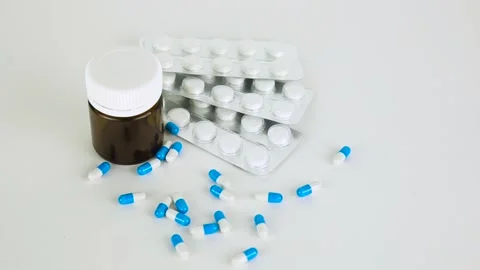Falling blue pills on pile of capsules on white background Stock Footage 174708517