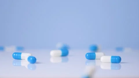 Falling blue white capsules on blue background. Stock Footage 258670219
