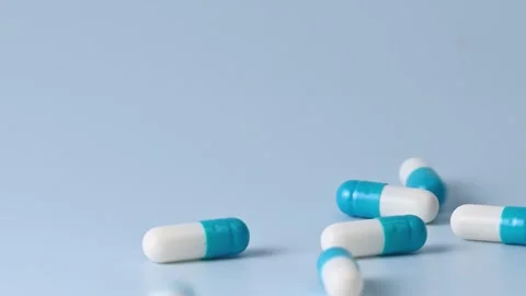 Falling blue white capsules on blue background closeup Stock Footage 258681912