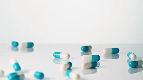 Falling blue white capsules on white background closeup Stock Footage 258751727