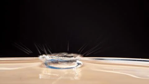 Falling brown drop on a black background Stock Photos