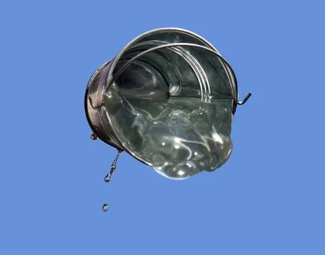 A falling buckets splashes water, on a background of blue sky. Stock Photos