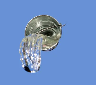 A falling buckets splashes water, on a background of blue sky. Stock Photos