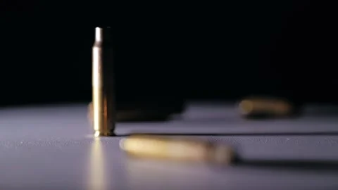 Falling bullet shells on table in dark light, concept of global power balance Stock Footage 318948981