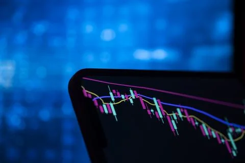 Falling candlestick chart on a smartphone screen against blue bokeh Stock Photos