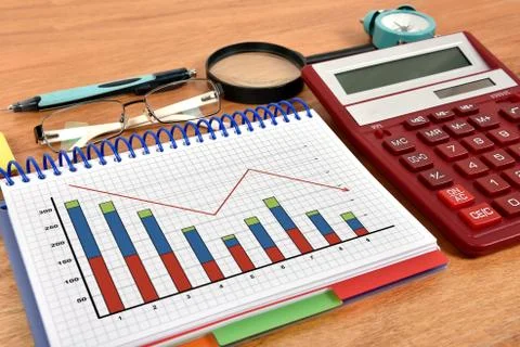 Falling chart in notebook and red calculator 库存照片