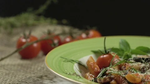 Falling cheese on a penne pasta with cherry tomatoes, aubergines, decorated Stock Footage 75058420