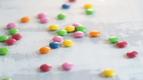 Falling close up candy drops on white wooden background. Video stock 107104470