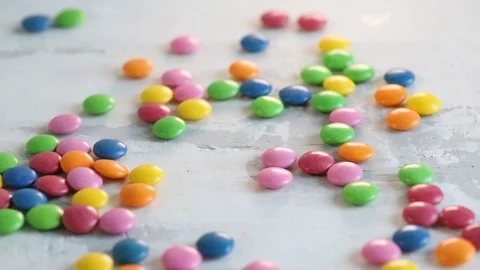 Falling close up candy drops on white wooden background. Stock Footage 107105020