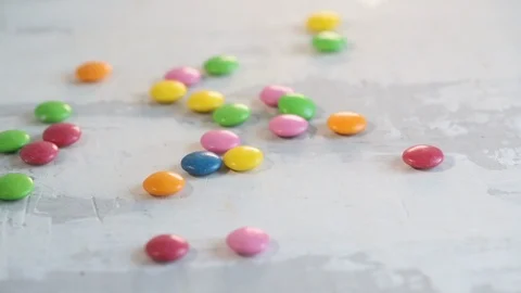 Falling close up candy drops on white wooden background. Stock Footage 107105169
