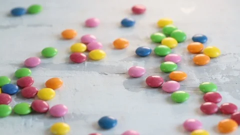Falling close up candy drops on white wooden background. Stock Footage 107105260