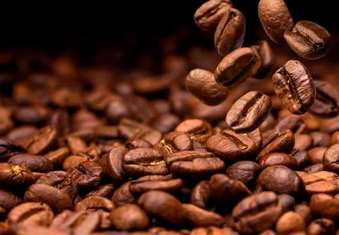 Falling coffee beans. Dark background with copy space, close-up Stock Photos