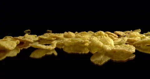 Falling Corn Flakes on black surface. Delicious breakfast cereals. Nutritious Stock Footage 146734888