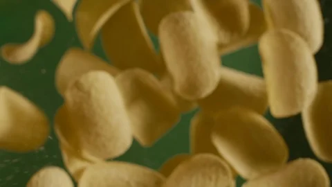 Falling crispy golden potato chips in slow motion on the green background, slow Stock Footage 115968162