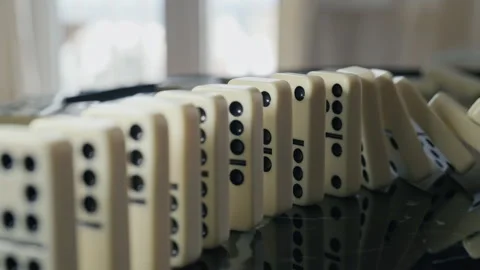 Falling domino pieces trigger a continuous chain reaction. Symbol of cause and e Vídeos de archivo 329793269