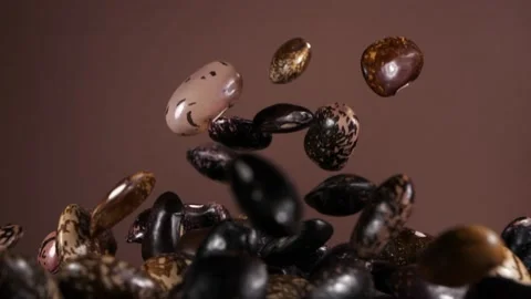 Falling down bean beans on a brown background. Super slow-motion. Видео 149924580