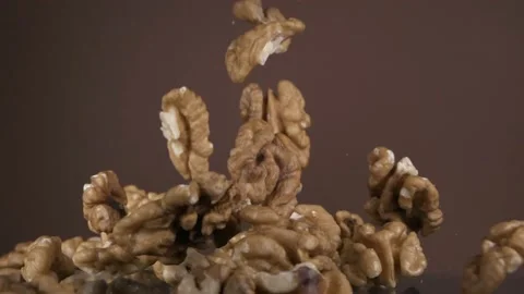 Falling down walnut kernels on a brown background. Super slow-motion. Stock Footage 149924474