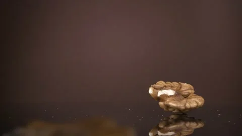 Falling down walnut kernels on a brown background. Super slow-motion. Stockbeeldmateriaal 149924544
