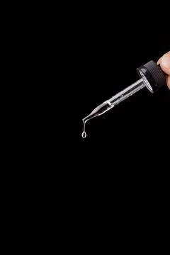 The falling drop of transparent liquid isolated on the black background Fotos de archivo