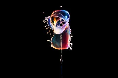 Falling drops of colored liquid, splashes on a black background 写真素材