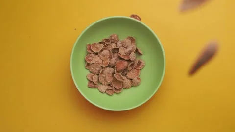 Falling dry corn flakes. Healthy breakfast on a yellow background. Flakes in Stock Footage 147673230