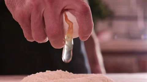 Falling egg into flour. Close up view of man hands breaking cracking raw egg Video stock 150778953